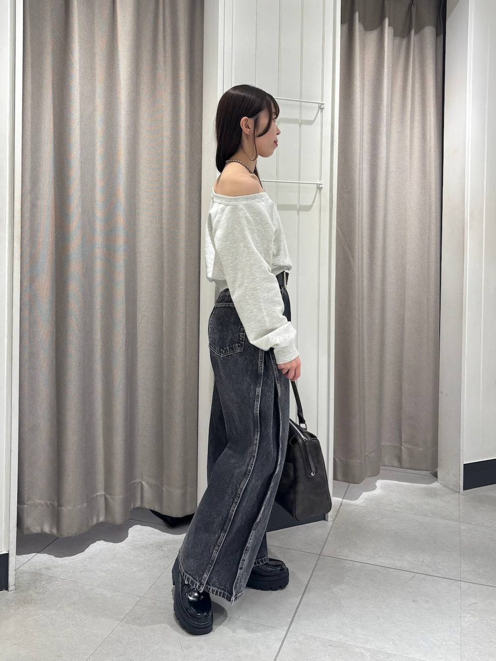 ベージュ系のスウェット、ブラック系のデニムパンツ、ブラウン系のボストンバッグを着用したレディースの冬コーディネートの3枚目の写真
