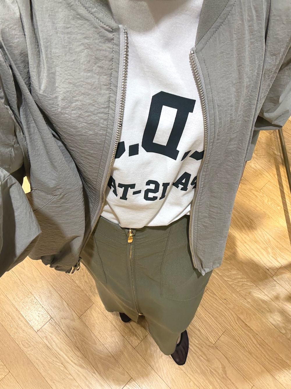 ホワイト系のTシャツ/カットソー、グリーン系のブルゾン、グリーン系のスカートを着用したレディースの春コーディネートの4枚目の写真