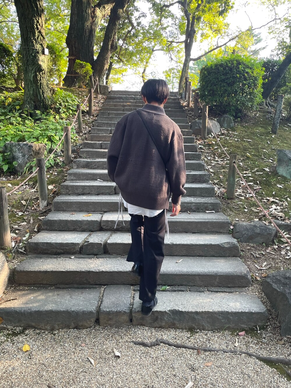 グレー系のシャツ/ブラウス、ブラック系のスラックス、グレー系のニット/セーターを着用したメンズの秋コーディネートの2枚目の写真