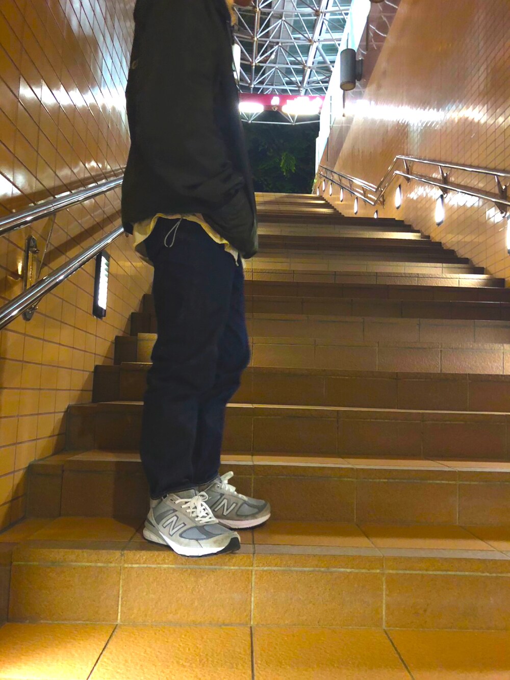 グリーン系のナイロンジャケット、ブルー系のデニムパンツ、グレー系のスニーカーを着用したメンズの春コーディネートの2枚目の写真