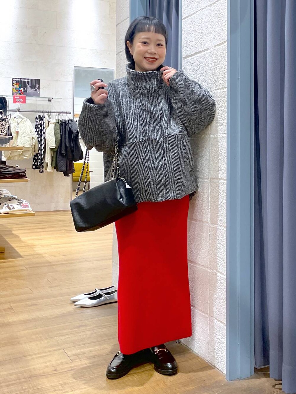 グレー系のブルゾン、レッド系のスカート、ブラック系のローファーを着用したレディースの冬コーディネートの2枚目の写真