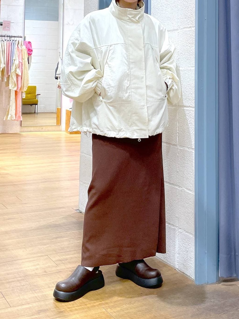 ブラウン系のスカート、ホワイト系のナイロンジャケット、ブラウン系のサンダルを着用したレディースの春コーディネートの3枚目の写真