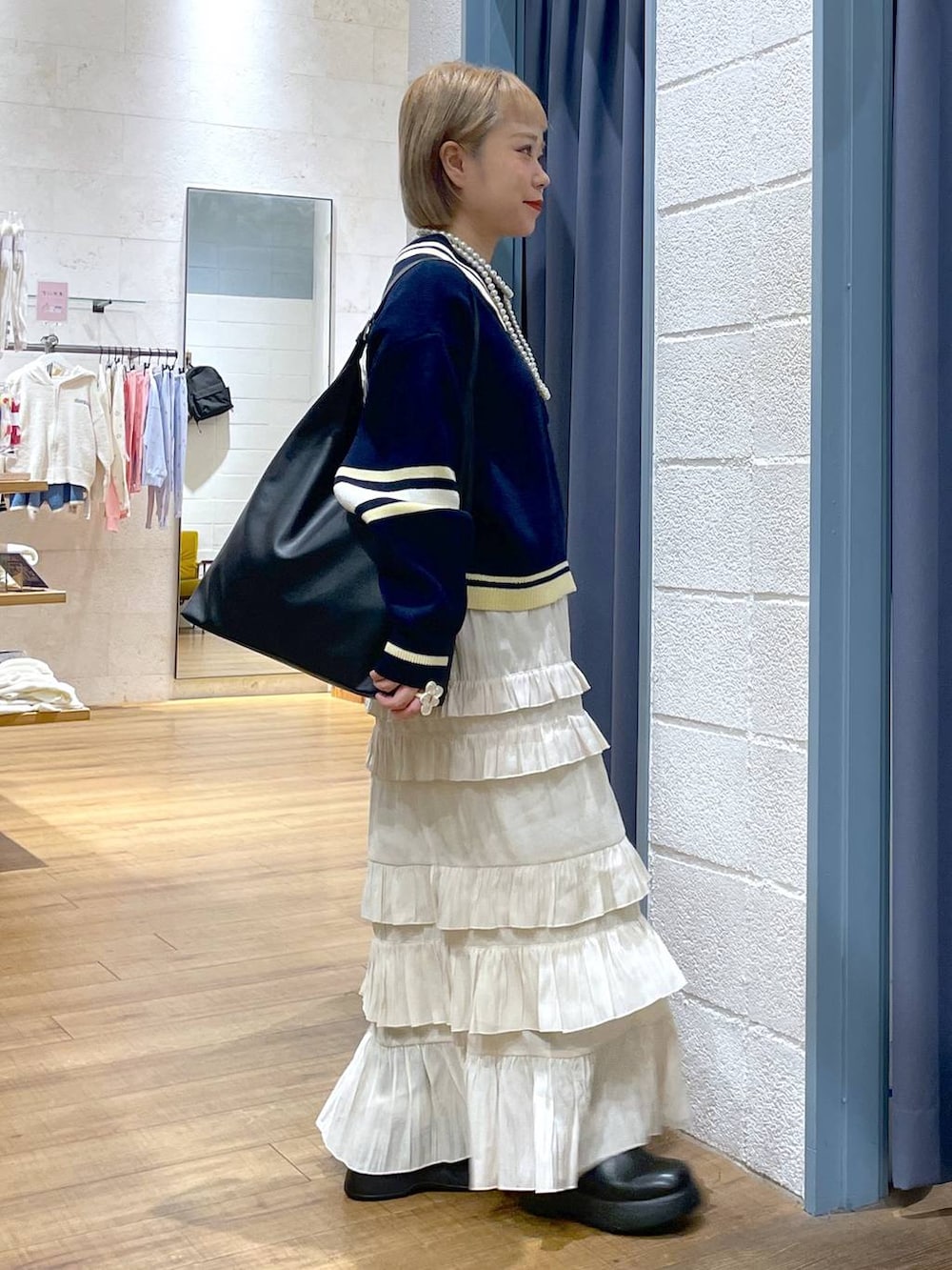 ブラック系のショルダーバッグ、ブルー系のニット/セーター、ブラック系のサンダルを着用したレディースの冬コーディネートの2枚目の写真