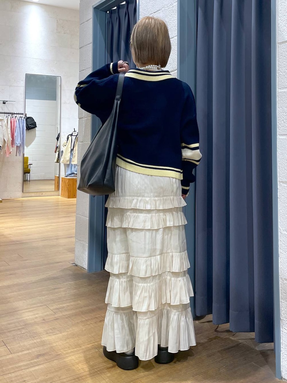 ブラック系のショルダーバッグ、ブルー系のニット/セーター、ブラック系のサンダルを着用したレディースの冬コーディネートの3枚目の写真