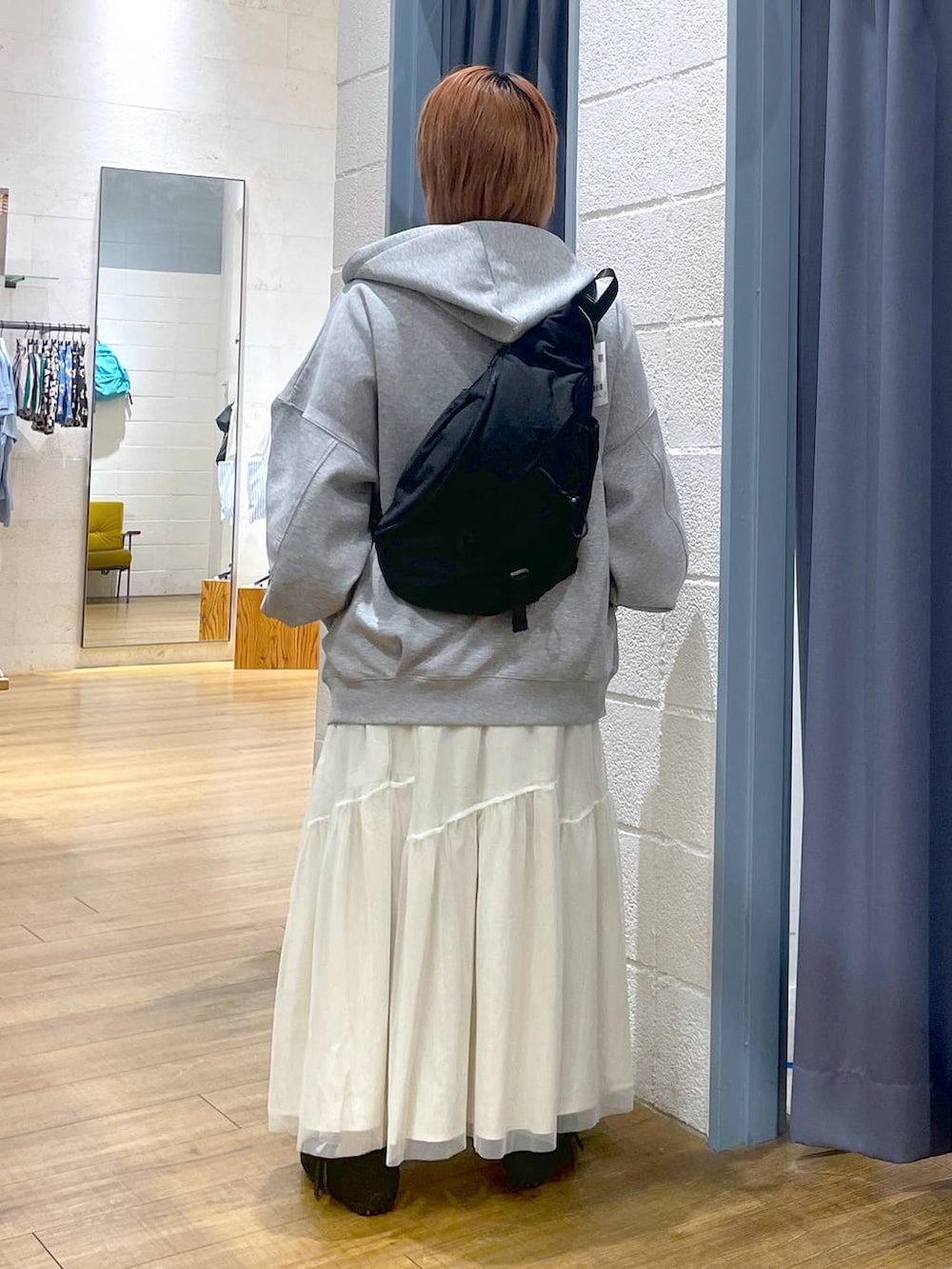 グレー系のパーカー、ブラック系のショルダーバッグ、ブラック系のスニーカーを着用したレディースの春コーディネートの5枚目の写真