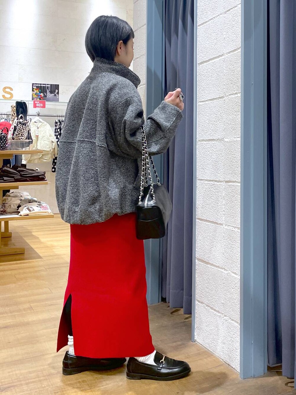 グレー系のブルゾン、レッド系のスカート、ブラック系のローファーを着用したレディースの冬コーディネートの3枚目の写真