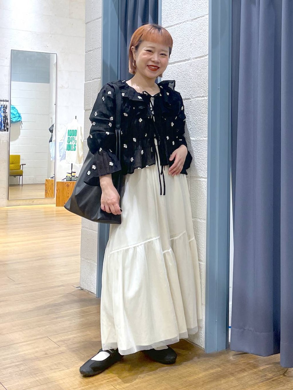 ブラック系のショルダーバッグ、ブラック系のスニーカー、ホワイト系のスカートを着用したレディースの春コーディネートの4枚目の写真