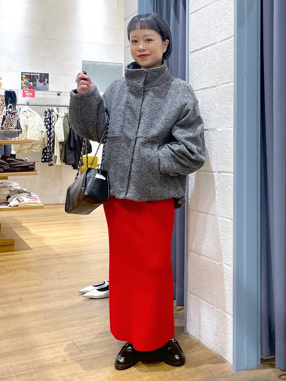 グレー系のブルゾン、レッド系のスカート、ブラック系のローファーを着用したレディースの冬コーディネートの5枚目の写真