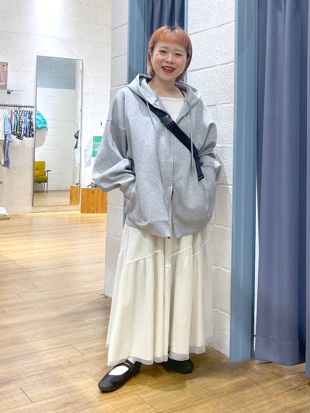 グレー系のパーカー、ブラック系のショルダーバッグ、ブラック系のスニーカーを着用したレディースの春コーディネートの3枚目の写真