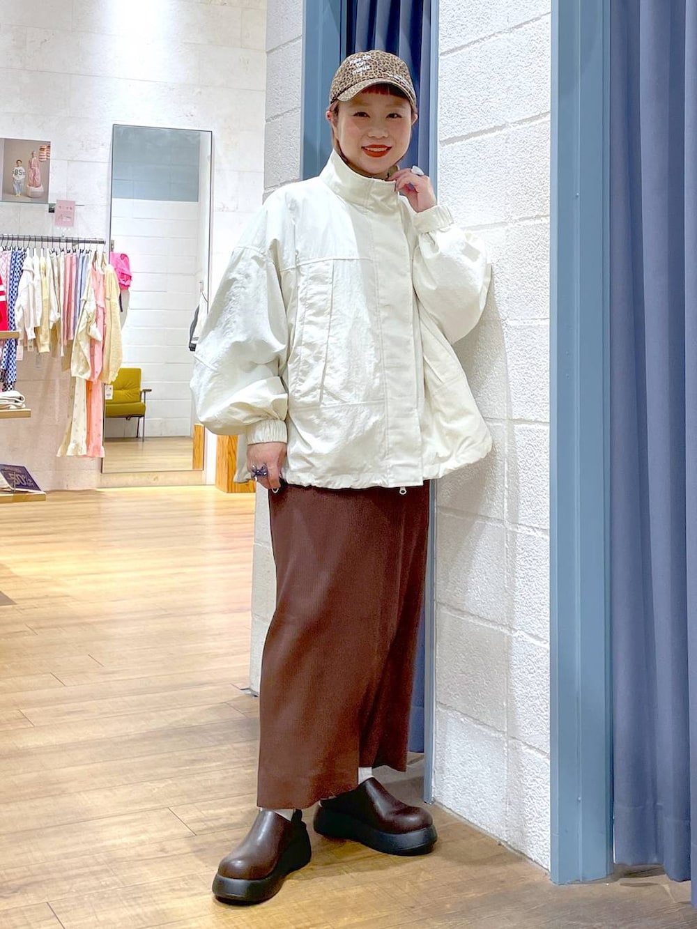 ブラウン系のスカート、ホワイト系のナイロンジャケット、ブラウン系のサンダルを着用したレディースの春コーディネートの2枚目の写真