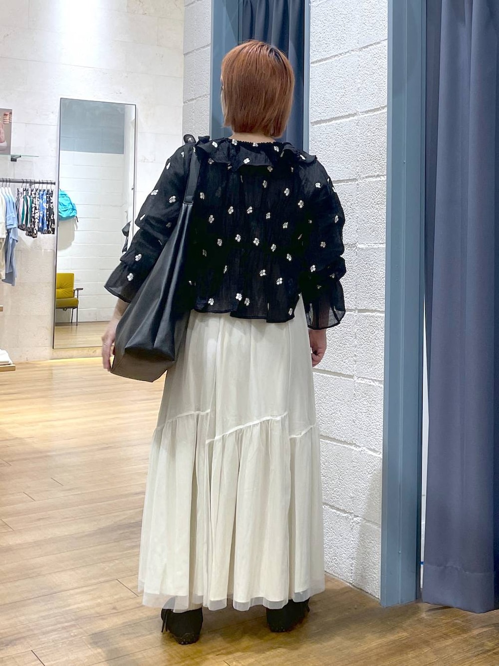 ブラック系のショルダーバッグ、ブラック系のスニーカー、ホワイト系のスカートを着用したレディースの春コーディネートの5枚目の写真