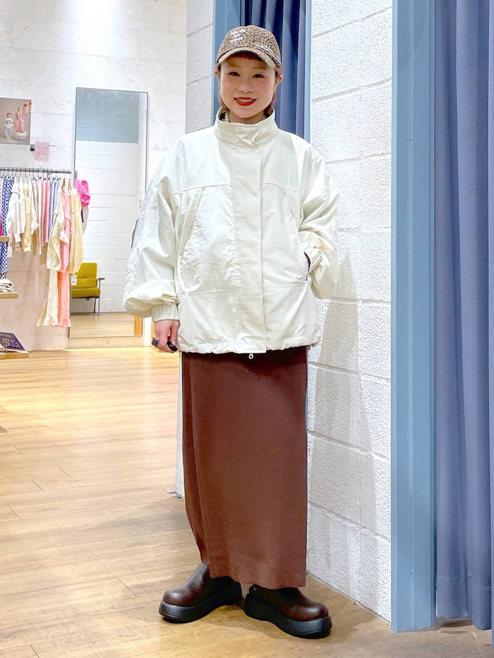ブラウン系のスカート、ホワイト系のナイロンジャケット、ブラウン系のサンダルを着用したレディースの春コーディネートの4枚目の写真