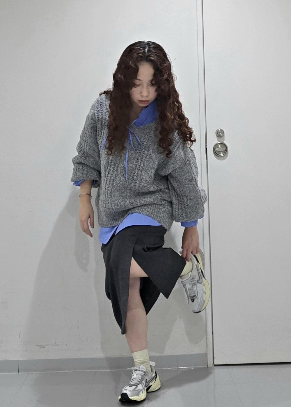 グレー系のスカート、ブルー系のニット/セーター、ブルー系のシャツ/ブラウスを着用したレディースの冬コーディネートの3枚目の写真