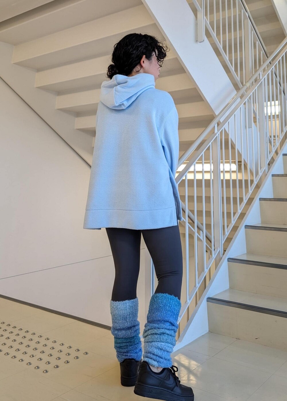 ブラック系のスニーカー、ブルー系のレッグウォーマー、グレー系のレギンス/スパッツを着用したレディースの冬コーディネートの5枚目の写真