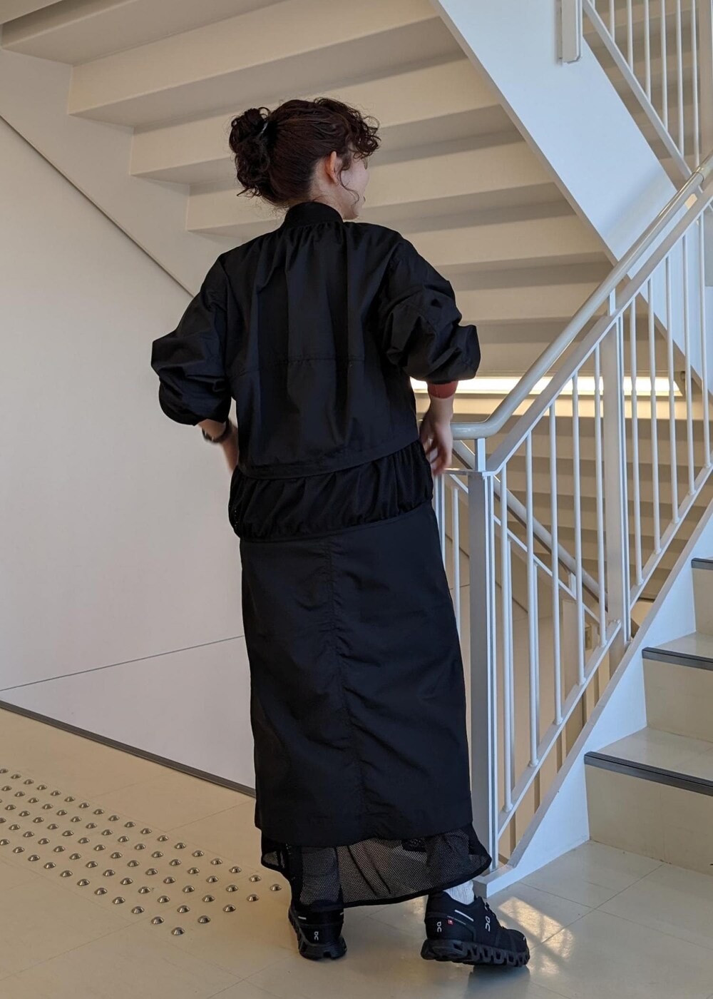 レッド系のTシャツ/カットソー、ブラック系のスニーカー、ブラック系のブルゾンを着用したレディースの春コーディネートの4枚目の写真