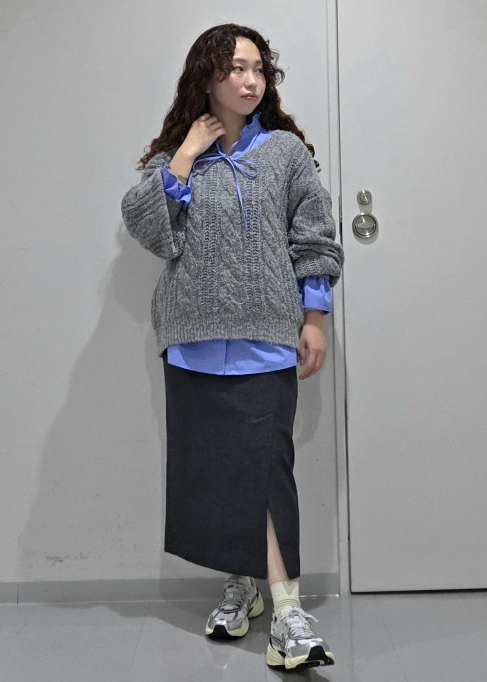 グレー系のスカート、ブルー系のニット/セーター、ブルー系のシャツ/ブラウスを着用したレディースの冬コーディネートの2枚目の写真