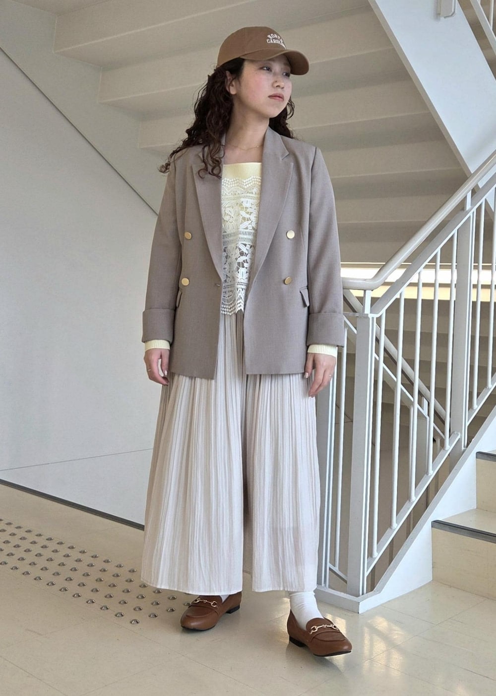 イエロー系のローファー、ベージュ系のテーラードジャケット、ベージュ系のニット/セーターを着用したレディースの春コーディネートの7枚目の写真