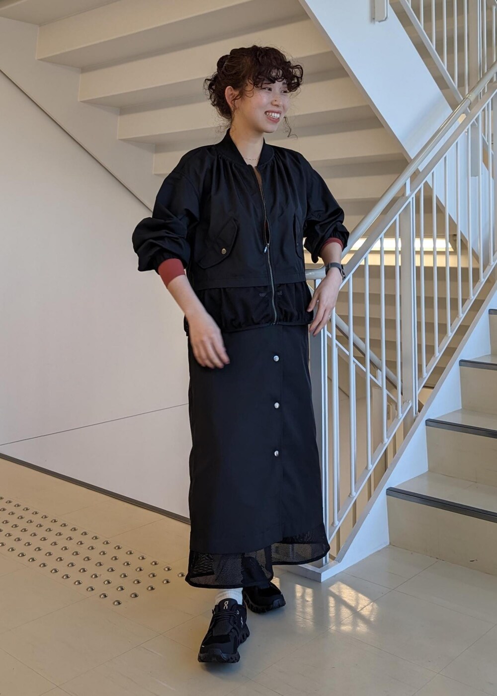 レッド系のTシャツ/カットソー、ブラック系のスニーカー、ブラック系のブルゾンを着用したレディースの春コーディネートの2枚目の写真