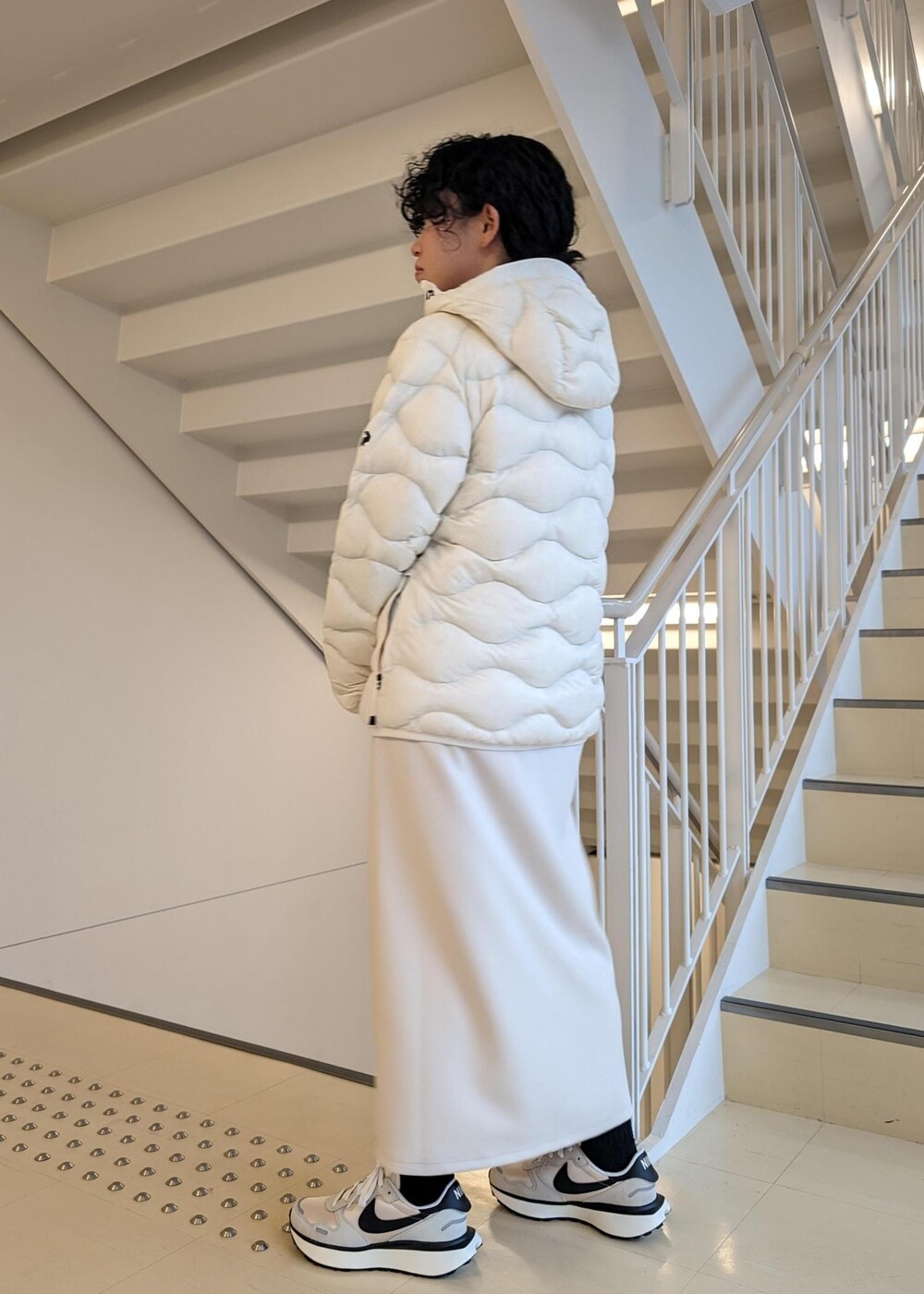 ホワイト系のスカート、ホワイト系のダウンジャケット/コート、ブラック系のTシャツ/カットソーを着用したレディースの冬コーディネートの4枚目の写真