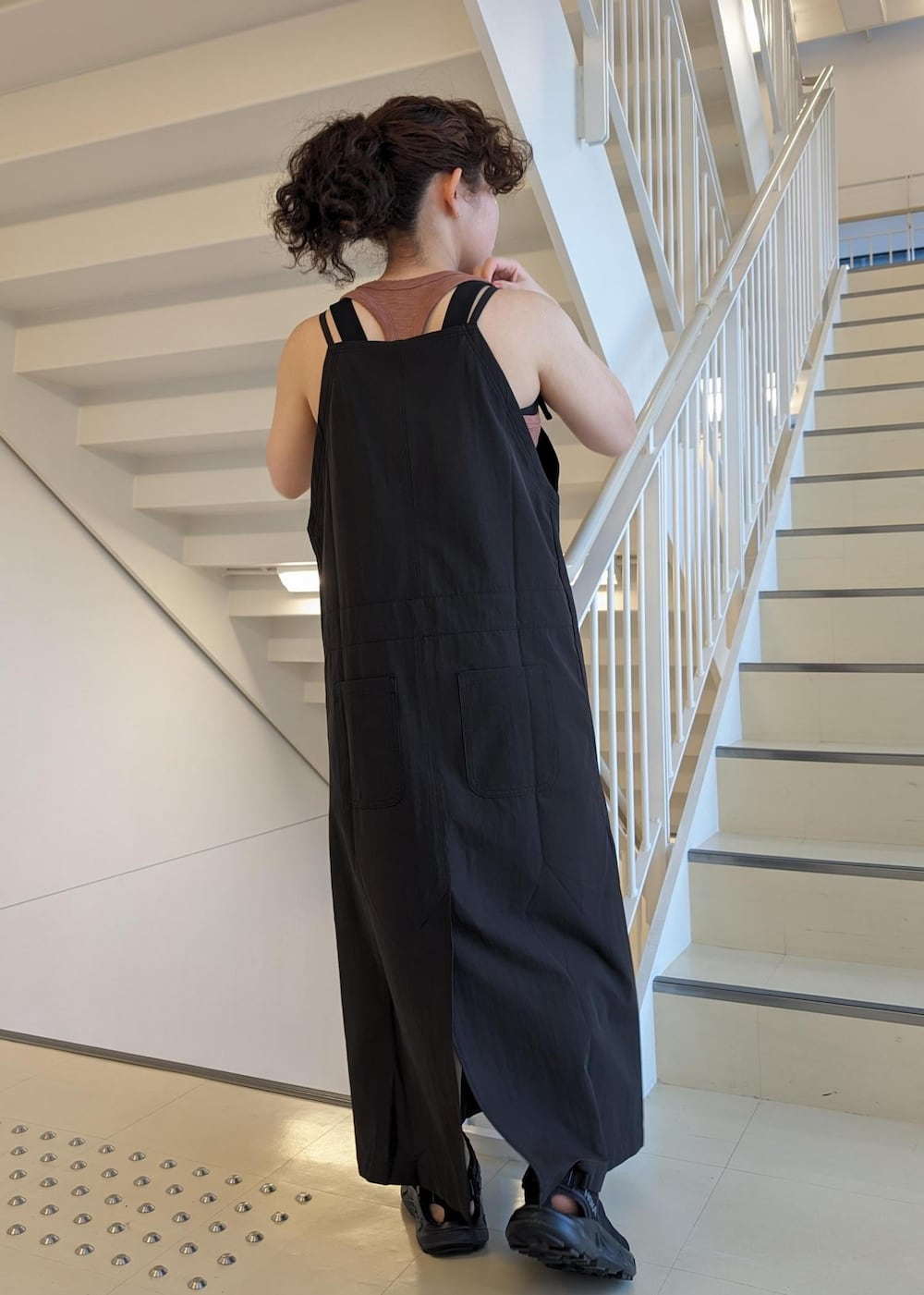 ブラック系のサンダル、ブラック系のワンピース、レッド系のタンクトップを着用したレディースの春コーディネートの4枚目の写真