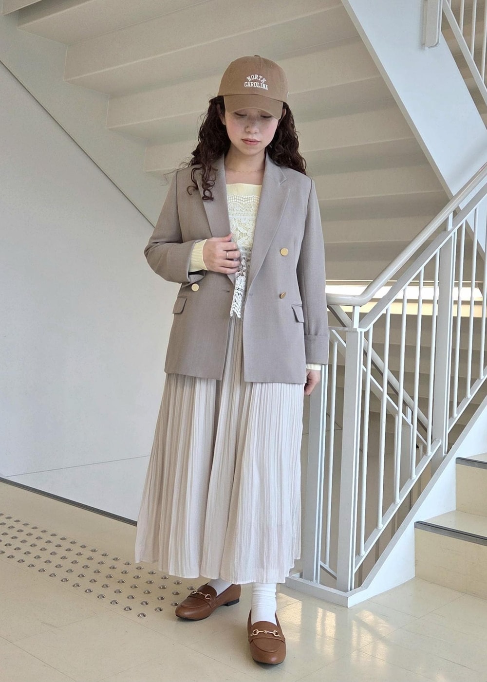 イエロー系のローファー、ベージュ系のテーラードジャケット、ベージュ系のニット/セーターを着用したレディースの春コーディネートの6枚目の写真