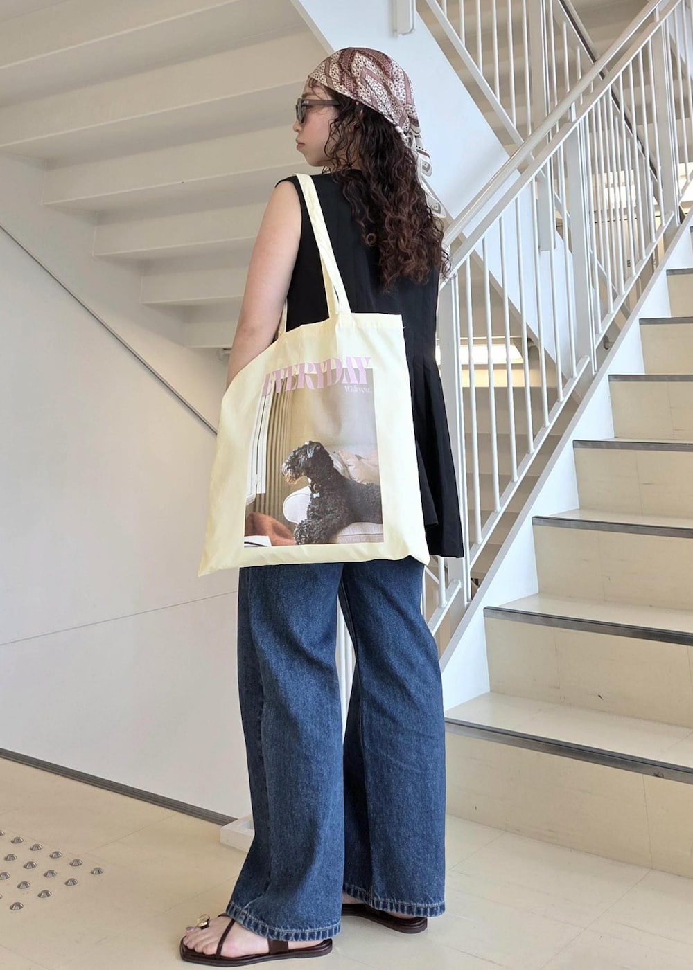ブルー系のデニムパンツ、ブラック系のサンダル、イエロー系のトートバッグを着用したレディースの夏コーディネートの8枚目の写真