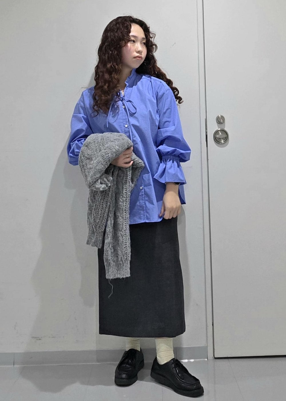 グレー系のスカート、ブルー系のニット/セーター、ブルー系のシャツ/ブラウスを着用したレディースの冬コーディネートの7枚目の写真