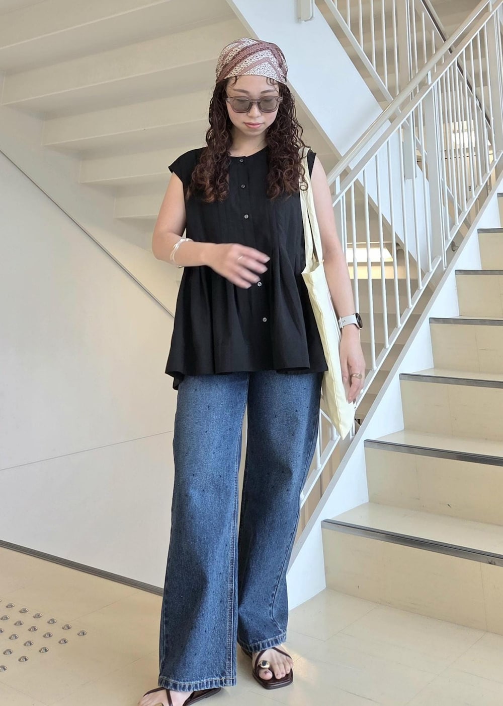 ブルー系のデニムパンツ、ブラック系のサンダル、イエロー系のトートバッグを着用したレディースの夏コーディネートの6枚目の写真