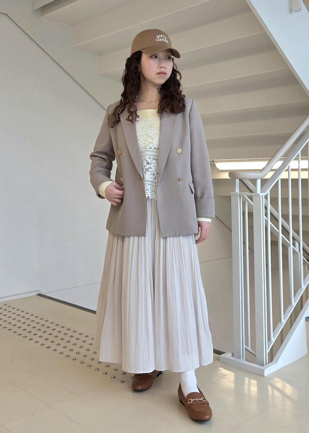 イエロー系のローファー、ベージュ系のテーラードジャケット、ベージュ系のニット/セーターを着用したレディースの春コーディネートの2枚目の写真