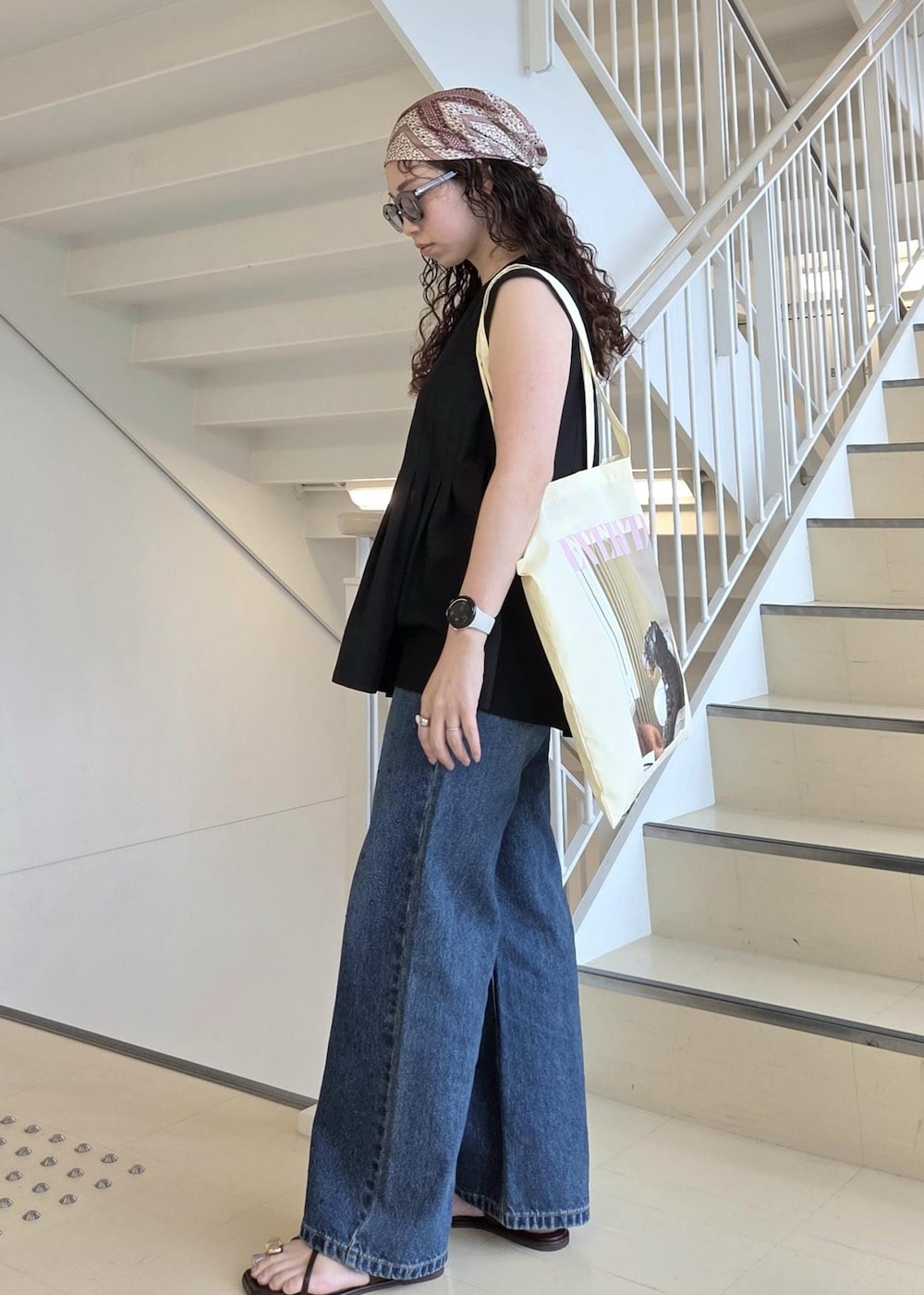 ブルー系のデニムパンツ、ブラック系のサンダル、イエロー系のトートバッグを着用したレディースの夏コーディネートの7枚目の写真