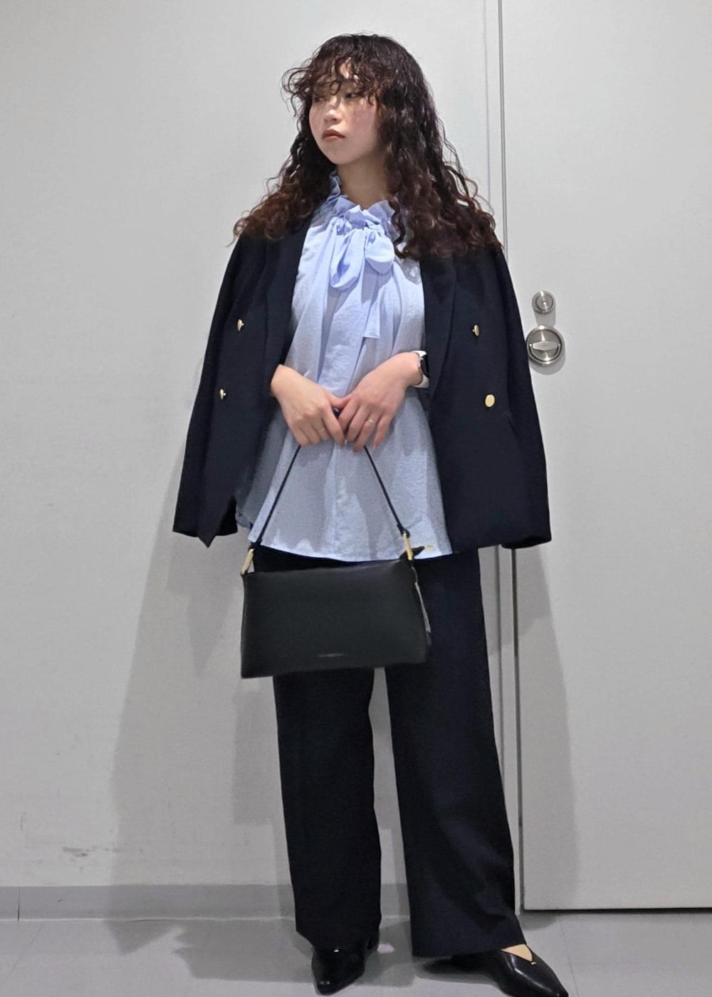 ブラック系のパンプス、ブルー系のシャツ/ブラウス、ブラック系のショルダーバッグを着用したレディースの冬コーディネートの2枚目の写真