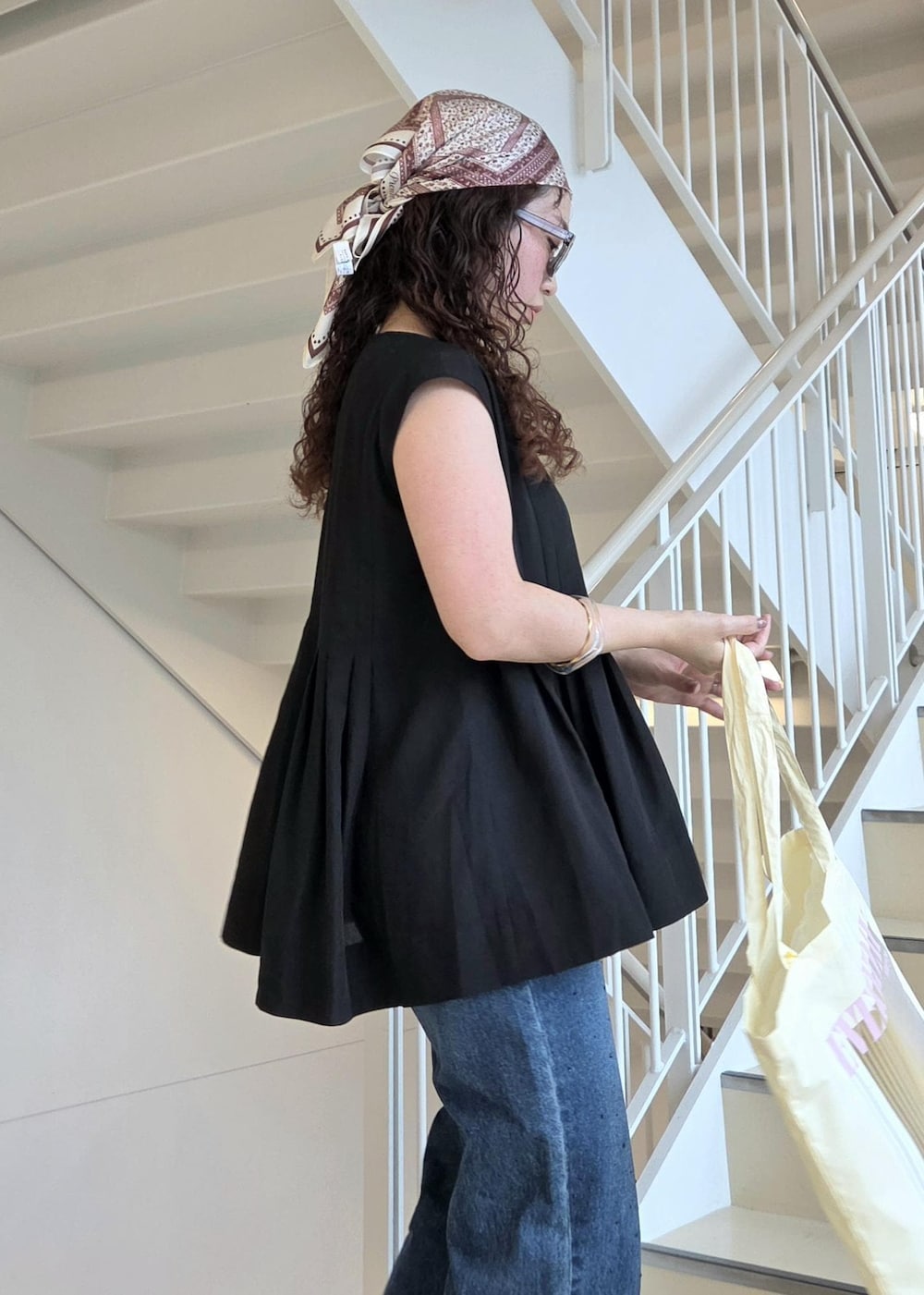 ブルー系のデニムパンツ、ブラック系のサンダル、イエロー系のトートバッグを着用したレディースの夏コーディネートの10枚目の写真
