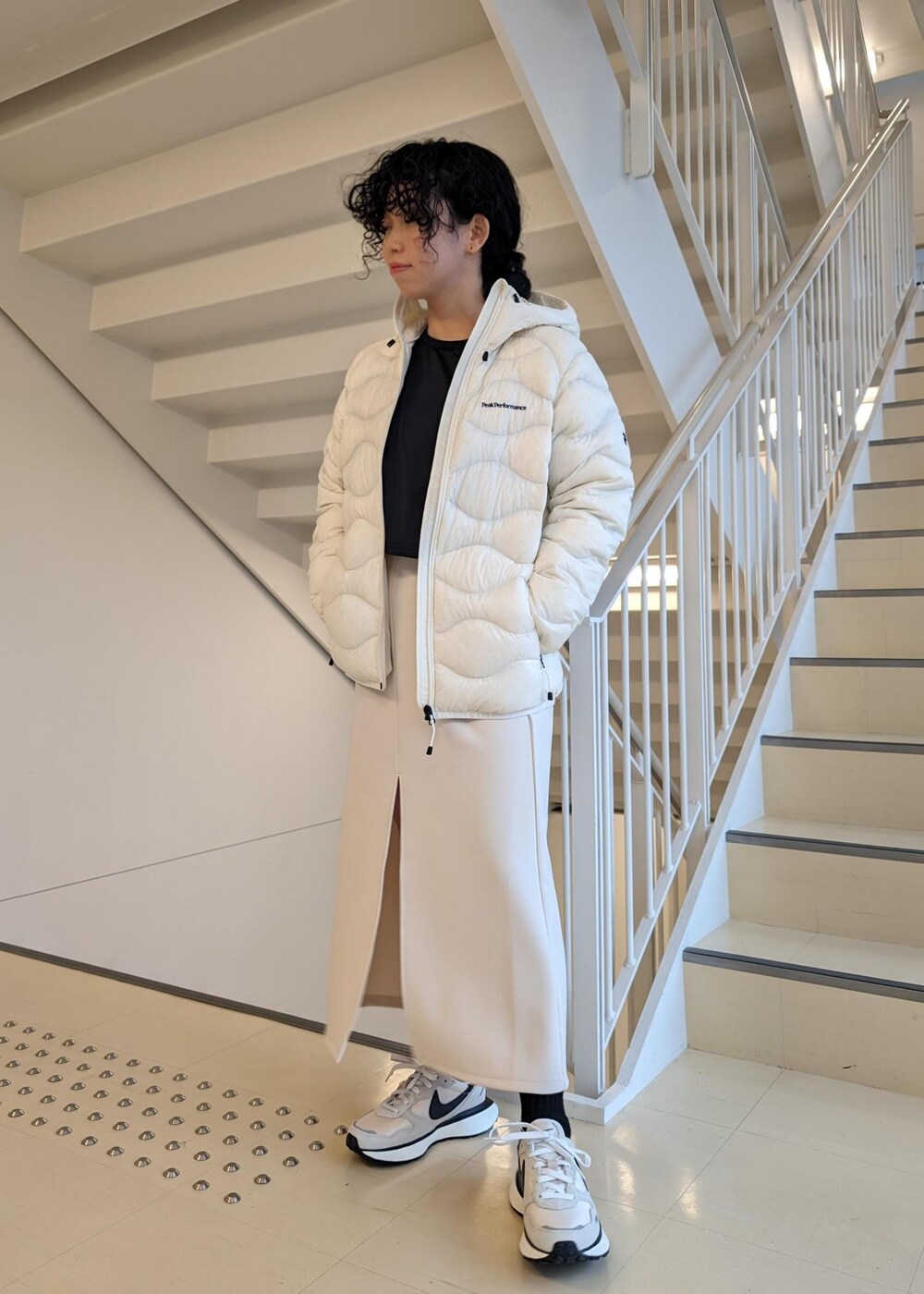 ホワイト系のスカート、ホワイト系のダウンジャケット/コート、ブラック系のTシャツ/カットソーを着用したレディースの冬コーディネートの2枚目の写真