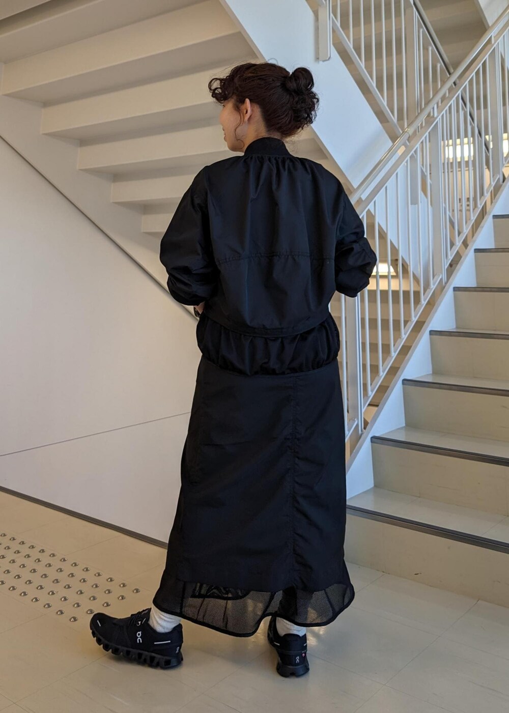 レッド系のTシャツ/カットソー、ブラック系のスニーカー、ブラック系のブルゾンを着用したレディースの春コーディネートの5枚目の写真