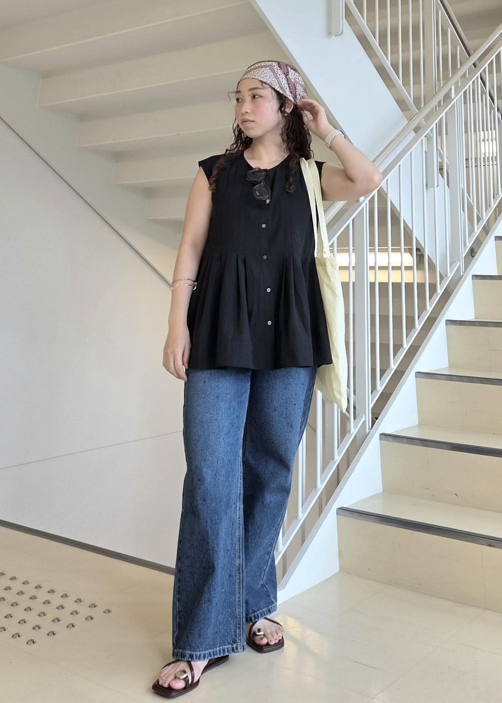 ブルー系のデニムパンツ、ブラック系のサンダル、イエロー系のトートバッグを着用したレディースの夏コーディネートの5枚目の写真