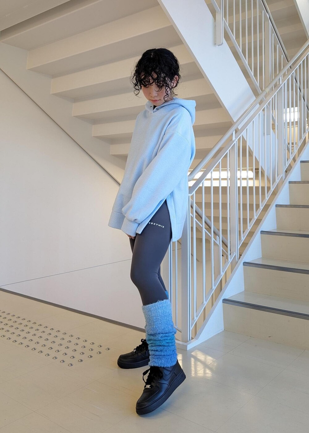 ブラック系のスニーカー、ブルー系のレッグウォーマー、グレー系のレギンス/スパッツを着用したレディースの冬コーディネートの2枚目の写真