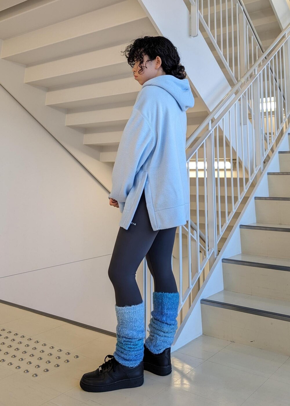 ブラック系のスニーカー、ブルー系のレッグウォーマー、グレー系のレギンス/スパッツを着用したレディースの冬コーディネートの4枚目の写真