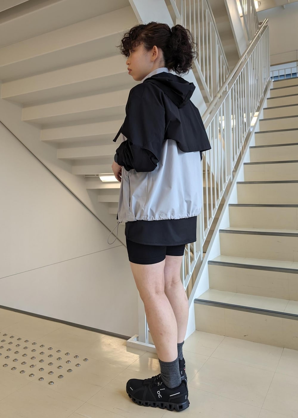 ブラック系のタンクトップ、ブラック系のスニーカー、グレー系のブルゾンを着用したレディースの春コーディネートの6枚目の写真