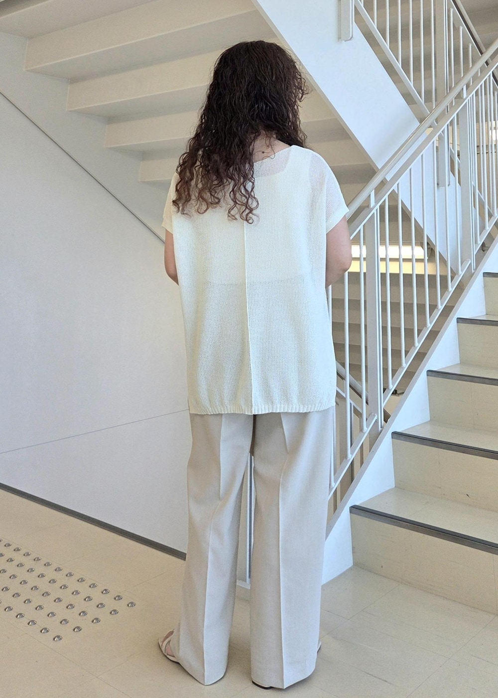 ベージュ系のその他パンツ、ホワイト系のハンドバッグ、ホワイト系のニット/セーターを着用したレディースの夏コーディネートの7枚目の写真