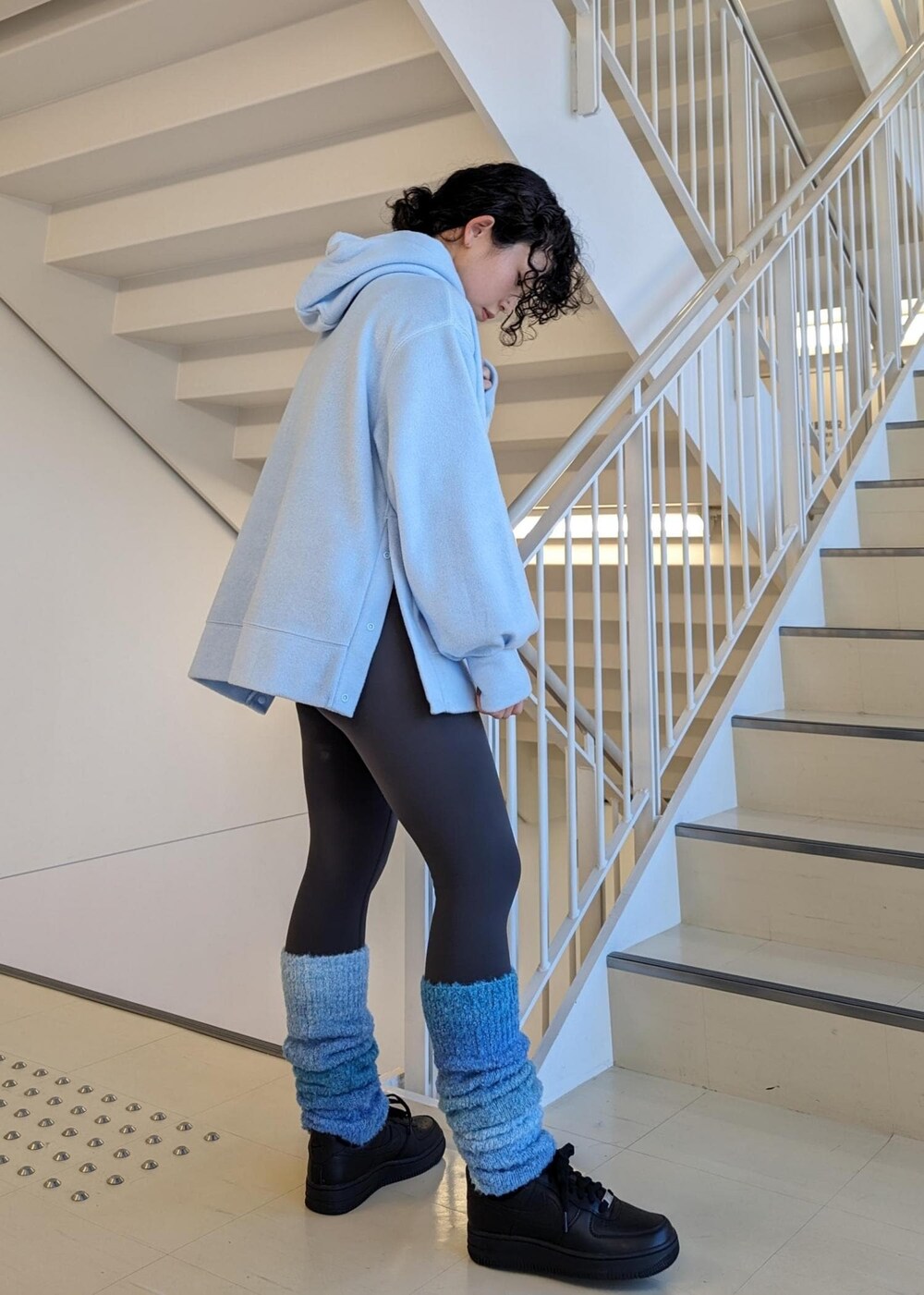 ブラック系のスニーカー、ブルー系のレッグウォーマー、グレー系のレギンス/スパッツを着用したレディースの冬コーディネートの3枚目の写真