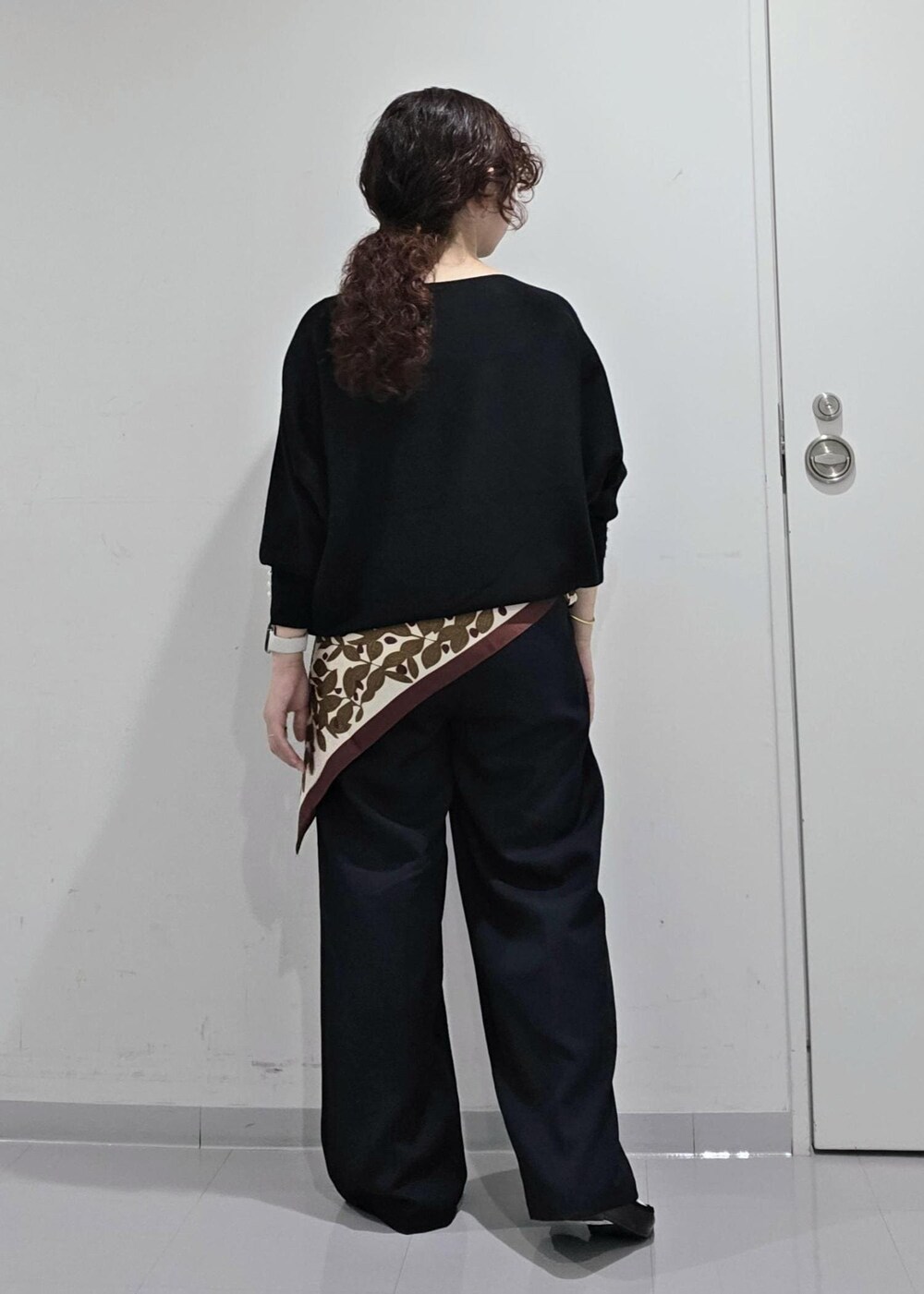 ブラウン系のニット/セーター、ブルー系のスラックス、ブラック系のバレエシューズを着用したレディースの秋コーディネートの6枚目の写真