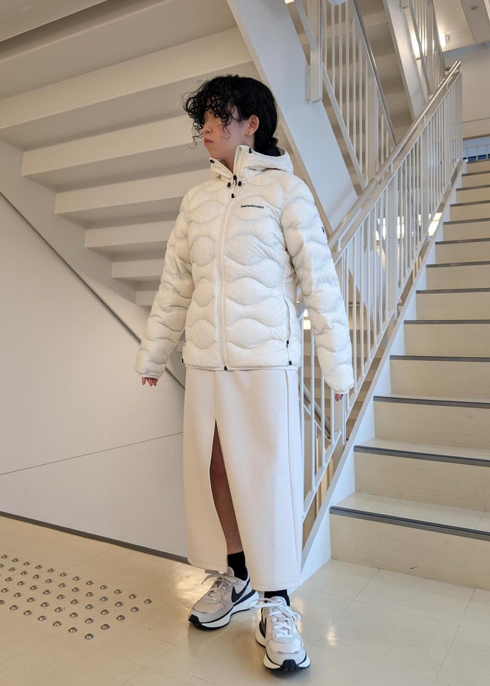 ホワイト系のスカート、ホワイト系のダウンジャケット/コート、ブラック系のTシャツ/カットソーを着用したレディースの冬コーディネートの5枚目の写真