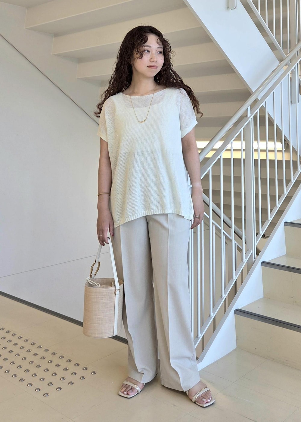 ベージュ系のその他パンツ、ホワイト系のハンドバッグ、ホワイト系のニット/セーターを着用したレディースの夏コーディネートの2枚目の写真