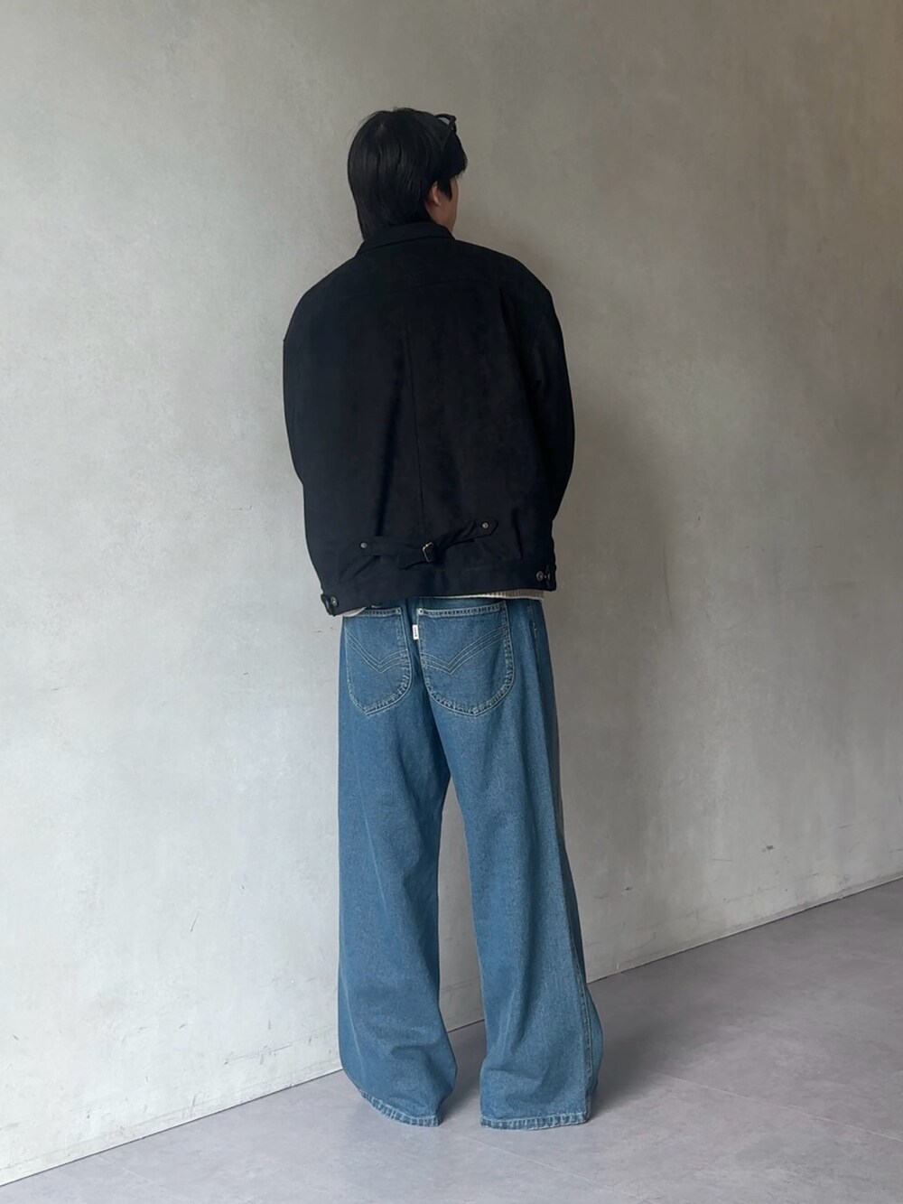 ブルー系のデニムパンツ、ベージュ系のニット/セーター、ブラック系のブルゾンを着用したメンズの秋コーディネートの3枚目の写真