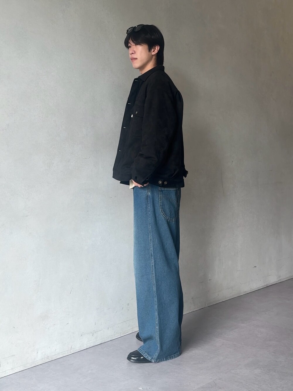 ブルー系のデニムパンツ、ベージュ系のニット/セーター、ブラック系のブルゾンを着用したメンズの秋コーディネートの2枚目の写真