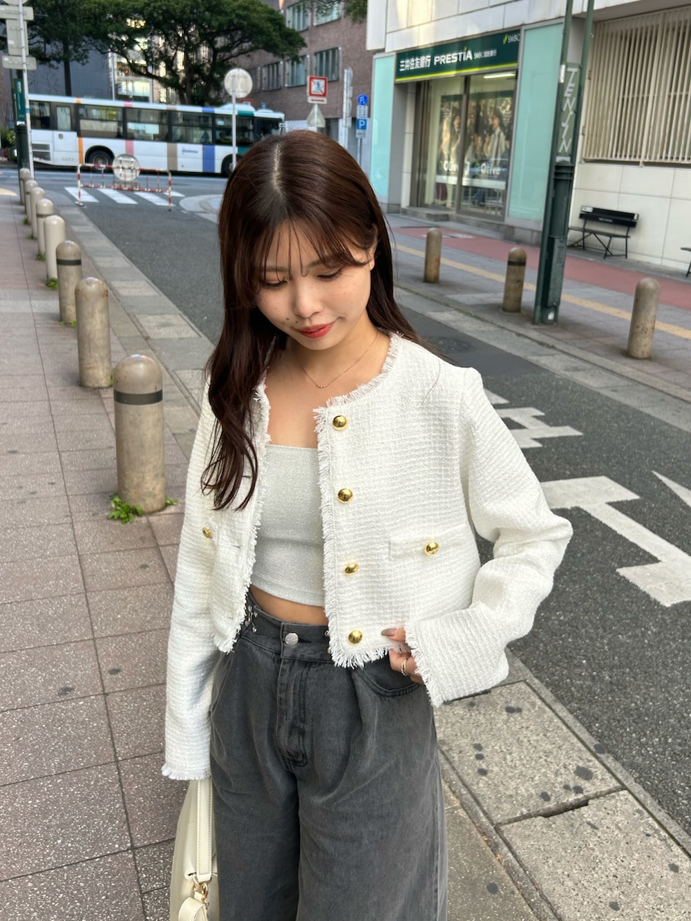 グレー系のデニムパンツ、ホワイト系のノーカラージャケット、ホワイト系のショルダーバッグを着用したレディースの冬コーディネートの2枚目の写真