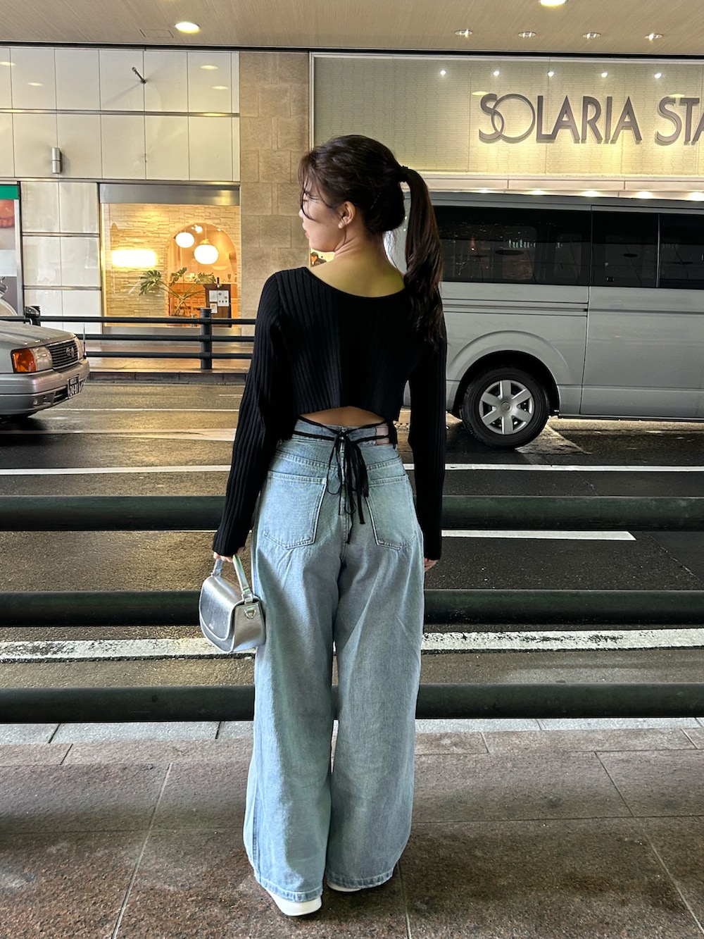 ブルー系のデニムパンツ、ブラック系のニット/セーター、シルバー系のショルダーバッグを着用したレディースの冬コーディネートの2枚目の写真