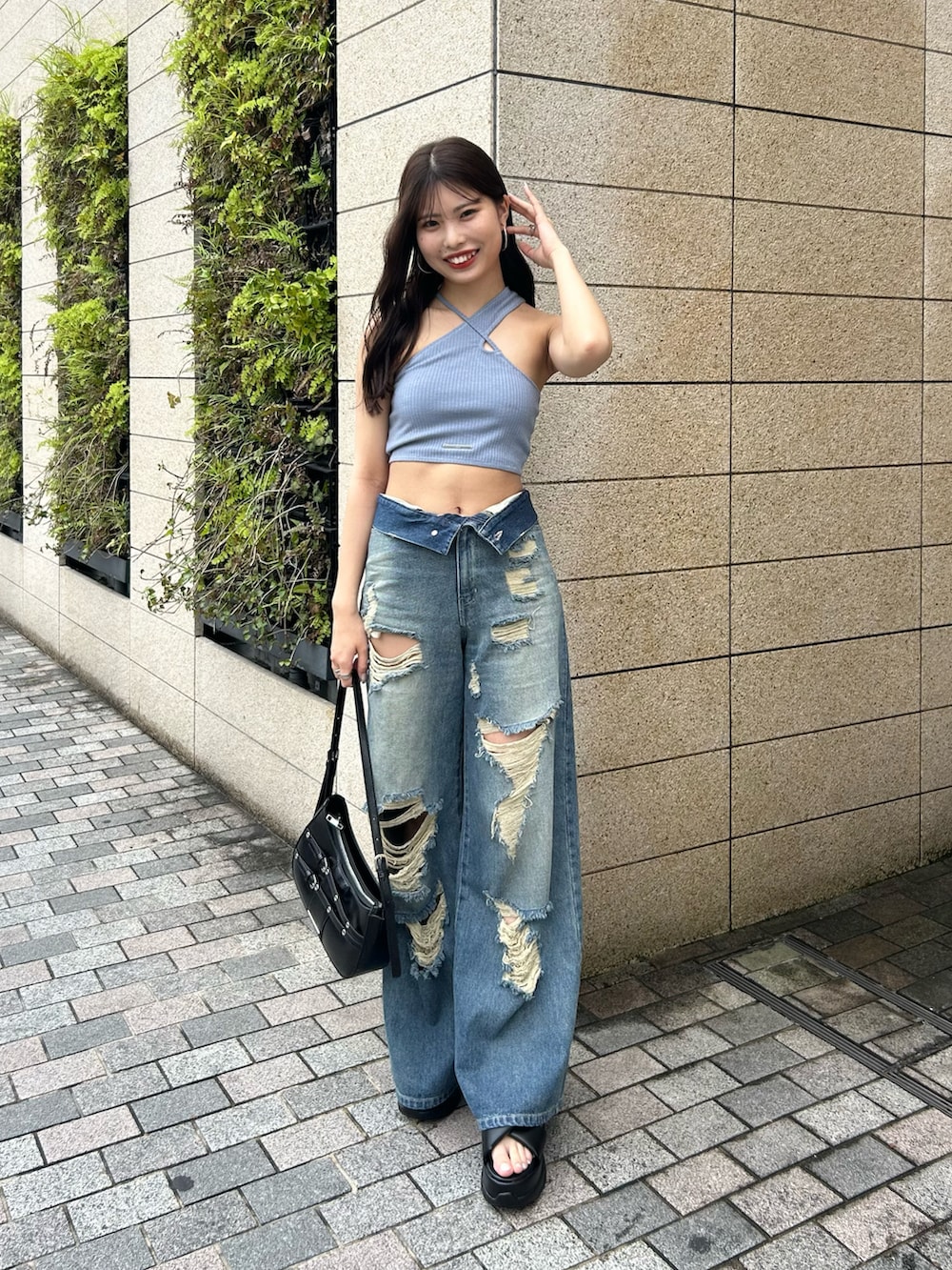 ブルー系のデニムパンツ、ブラック系のショルダーバッグ、ブラック系のサンダルを着用したレディースの春コーディネートの5枚目の写真