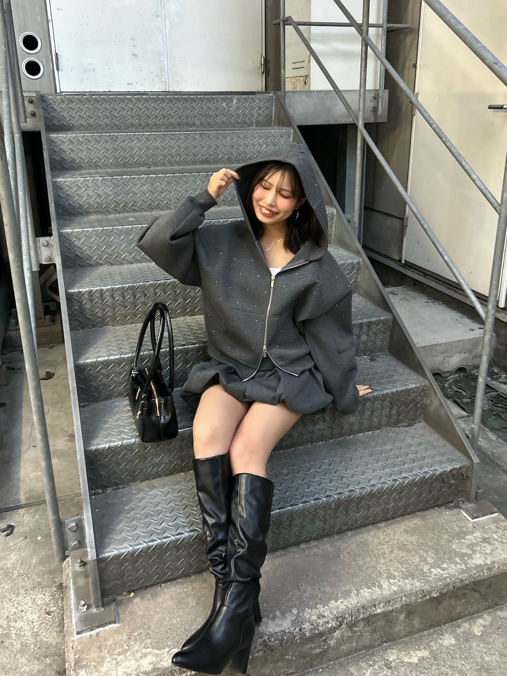 グレー系のパーカー、グレー系のスカート、ブラック系のボストンバッグを着用したレディースの秋コーディネートの6枚目の写真