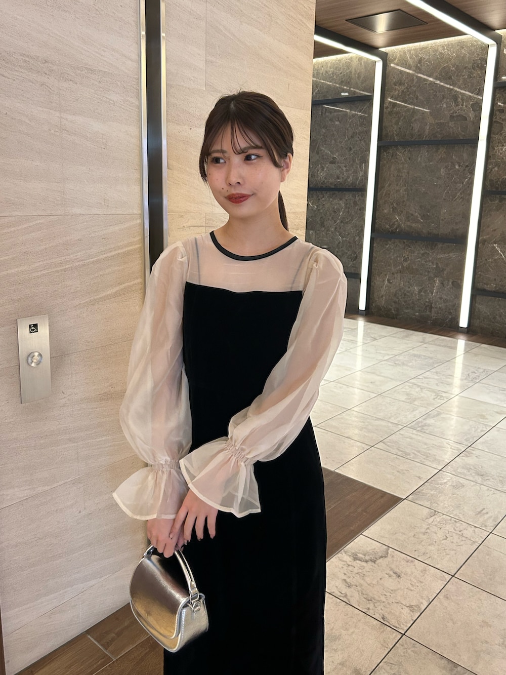 ブラック系のドレス、シルバー系のショルダーバッグ、シルバー系のパンプスを着用したレディースの春コーディネートの3枚目の写真